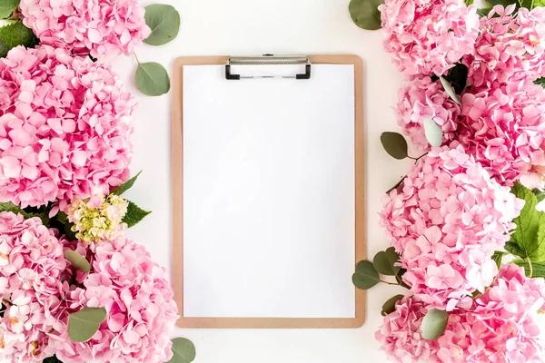 Carved, white frame decorated of pink hydrangea flowers on white background. Floral concept. Flat lay, top view.