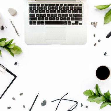 Ofis masası Kağıt boş, yeşil yapraklı çalışma alanı çerçevesi. Dizüstü bilgisayar, beyaz arka planda gözlük. Dergiler, web siteleri, medya. Düz yatış, üst görünüm