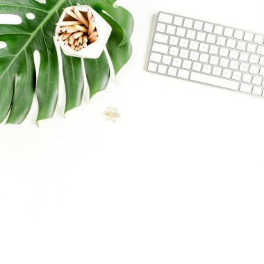 Bilgisayarlı kadın ofis masası çalışma alanı, tropikal palmiye yaprakları, beyaz arka planda aksesuarlar. Üst görünüm kadınsı arkaplan. 