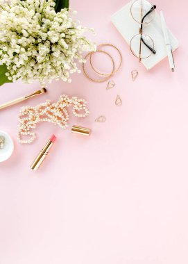 Ofis masasında bilgisayar, leylak ve dosya var. Dergiler. Üst Manzara Düz Yatıyordu. Merkez ofis çalışma alanı. Pembe arka planda kadın moda aksesuarları