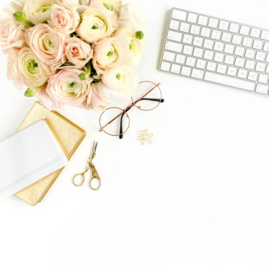 Tarz sahibi kadınların ofis masası. Bilgisayarlı çalışma alanı, buket ranunculus ve güller, beyaz arka planda pano. Düz yatıyordu. Üst görünüm.