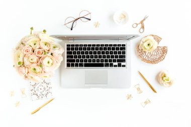 Tarz sahibi kadınların ofis masası. Laptop, bilgisayar, buket ranunculus ve güllerle çalışma alanı, beyaz arka planda pano. Düz yatıyordu. Üst görünüm.
