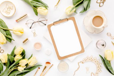 Panosu, altın aksesuarları, sarı lale çiçekleri, kırtasiyesi olan kadın çalışma odası. Düz yatış, üst görünüm