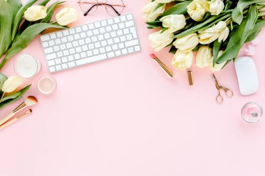 Bilgisayarlı kadın çalışma alanı, lale çiçekleri buketi, altın aksesuarlar, pembe arka planda günlük. Düz uzanmış kadınların ofis masası. Üst görünüm