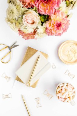 Ev ofisinin masası düzdü. Pembe güllü kadın çalışma alanı, yıldız çiçeği buketi, altın aksesuarlar, beyaz arka planda günlük. Üst görünüm.