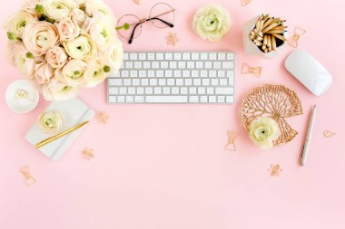 Tarz sahibi, pembe kadınların ofis masası. Bilgisayarlı çalışma alanı, buket ranunculus ve güller, pembe arka planda pano. Düz yatıyordu. Üst görünüm.