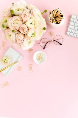 Tarz sahibi, pembe kadınların ofis masası. Çiçek buketi ve güllerle dolu çalışma alanı, pembe arka planda pano. Düz yatıyordu. Üst görünüm.