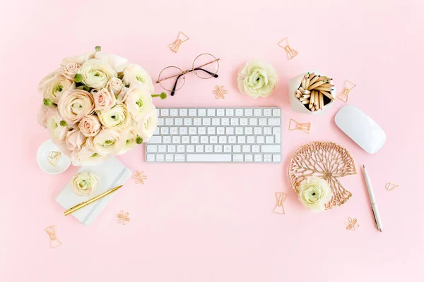 Stylized, pink womens home office desk. Workspace with computer, bouquet ranunculus and roses, clipboard on pink background. Flat lay. Top view. — Stock Photo, Image