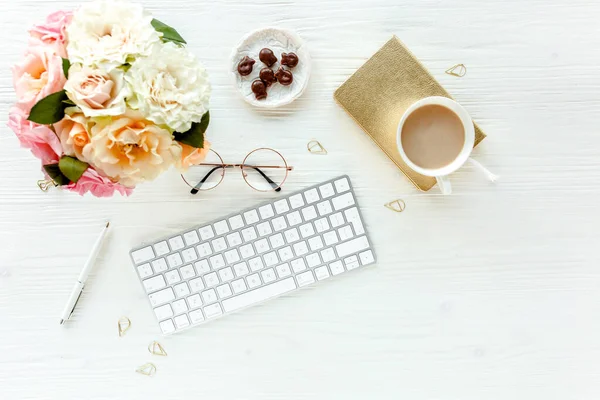 Flat lay womens office desk. Female workspace with computer, pink roses flowers, accessories, golden diary, glasses on white background. Top view — Stock Photo, Image