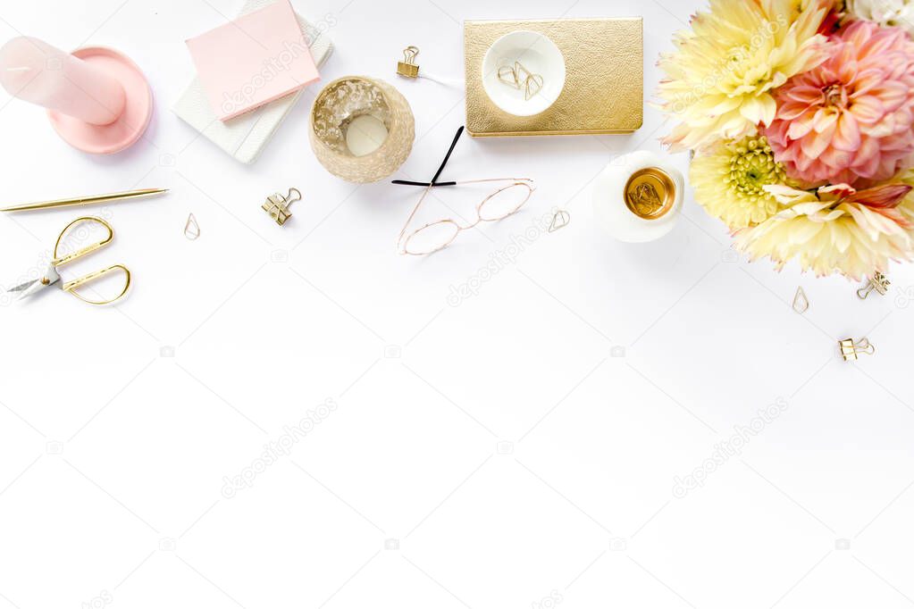 Flat lay home office desk. Female workspace with pink and beige roses flowers, accessories, gold and pink diary, white wooden background. Top view 
