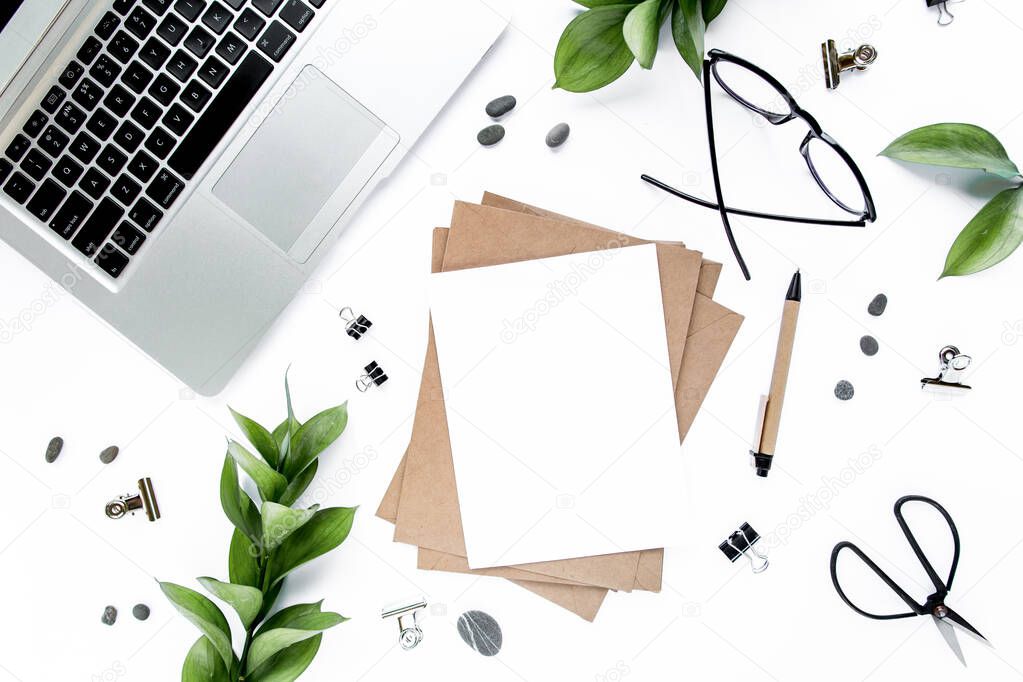 office desk workspace with paper blank, green leaves. Laptop, glasses on white background. Magazines, websites, social media. Flat lay, top view.