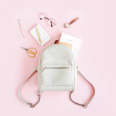 Pembe arka plan manzaralı kadın bej sırt çantası ve moda aksesuarları. Düz bir kadınsı görünüş. Üst görünüm.