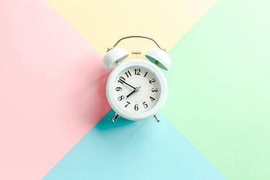 Renkli arka planda beyaz alarmlı saat. Moda minimal tarzı. Güzellik ve moda konsepti. Düz kompozisyon. Üst görünüm.