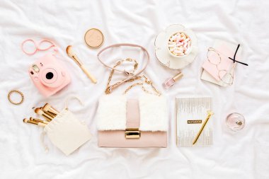 Pembe el çantası, kamera, makyaj fırçası, kozmetik, güneş gözlüğü, beyaz arka planda aksesuarlar. Düz kompozisyon. Sosyal medya. Üst Manzara. Düz yatıyordu. 