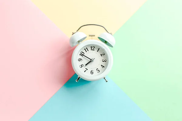 White alarm clock on colorful background. Trendy minimal style. Beauty and fashion concept. Flat lay composition. Top view. — Stock Photo, Image