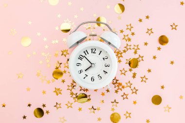Alarmlı saat, altın yıldızlı konfeti kaplıydı. Pembe, şenlikli bir arka planda süsleme vardı. Noel ya da yeni yıl şablonu. Renkli bir kutlama, doğum günü.
