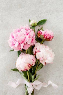 Gri taş masanın üzerinde güzel pembe şakayık çiçekleri ve metin için fotokopi alanı. Düz stil, üst görünüm