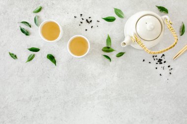 İki beyaz çay fincanı ve yeşil çay yapraklı çaydanlık ile bitki çayı. Düz yerde, üst tarafta. Çay konsepti