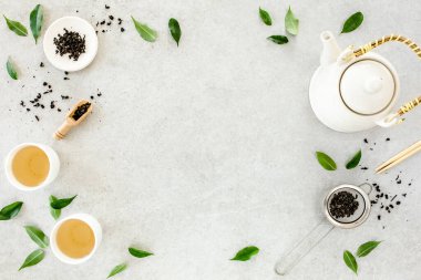 İki beyaz çay fincanı ve yeşil çay yapraklı çaydanlık ile bitki çayı. Düz yerde, üst tarafta. Çay konsepti