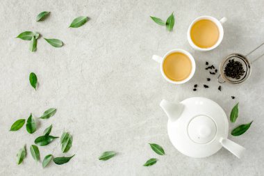İki beyaz çay fincanı ve yeşil çay yapraklı çaydanlık ile bitki çayı. Düz yerde, üst tarafta. Çay konsepti