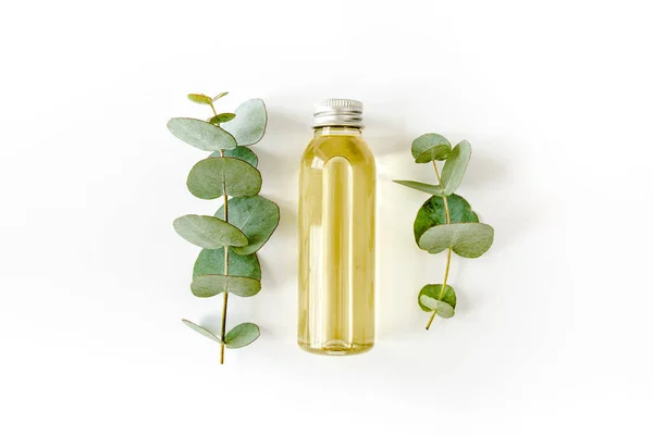 Bottle of eucalyptus essential oil, eucalyptus leaves on white background. Natural, Organic cosmetics products. Flat lay, top view. — Stock Photo, Image