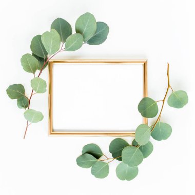 Altın çerçeve yeşil dallar ve beyaz arka planda okaliptüs yapraklarıyla süslenmiştir. Düz uzan, üst görünüm