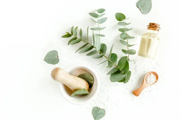 Bottle of eucalyptus essential oil, eucalyptus leaves on white background. Natural Organic cosmetics products. Flat lay, top view. — Stock Photo, Image