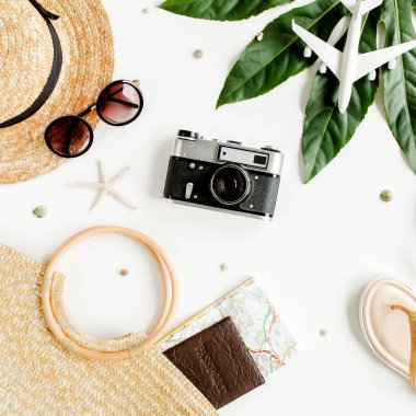 Kadın plaj aksesuarları: rattan çanta, hasır şapka, tropik palmiye yaprakları, beyaz arka planda uçak. Seyahat kavramı. Yaz arkaplanı. 