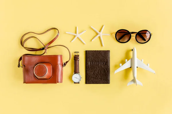 Концепция аксессуаров для путешественников на желтом фоне. Ретро-камера, модель самолета, самолет, солнечные очки. Летний фон. — стоковое фото