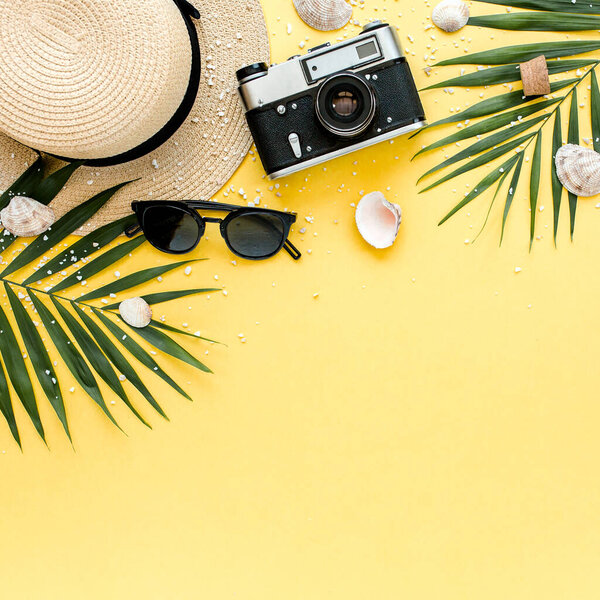 Traveler accessories, tropical palm leaf branches on yellow background with empty space for text. Summer background. Flat lay, top view.