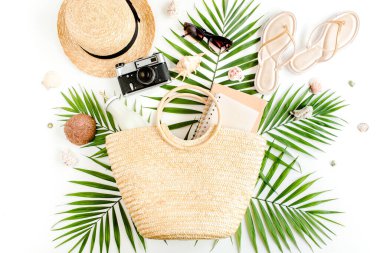 Kadın plaj aksesuarları: rattan çanta, hasır şapka, beyaz arka planda tropikal palmiye yaprakları. Seyahat kavramı. 