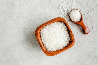 Gri taş masadaki kepçeli ahşap kasede tuz. Deniz tuzu düzlüğü, üst manzara.. 