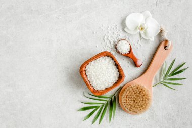 Spa cildi konsepti. Doğal organik spa ürünleri, deniz tuzu, masaj fırçası ve yukarıdaki gri mermer masada tropik palmiye yaprakları.. 