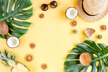 Tropikal çerçeve, arka planda egzotik meyveler ve sarı arka planda tropikal palmiye yaprakları. Düz yatış, üst görünüm