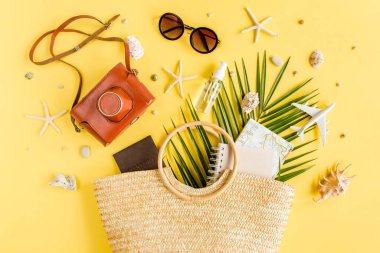 Kadın plaj aksesuarları: rattan çanta, retro kamera, tropikal palmiye yaprakları, model uçak, sarı arka planda uçak. 