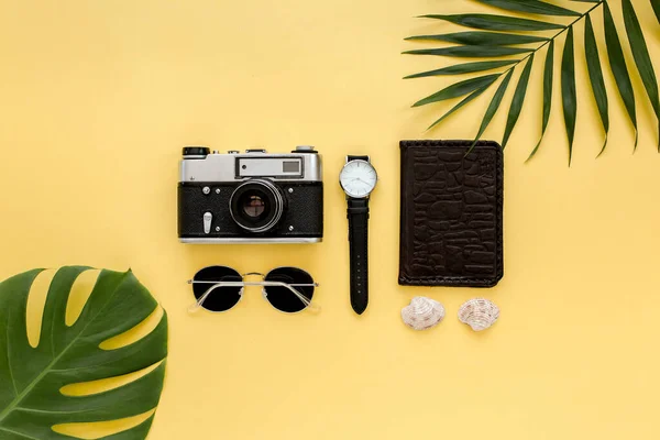 Accesorios para viajeros sobre fondo amarillo con hoja de palma, cámara y gafas de sol. Piso tendido, vista superior. — Foto de Stock