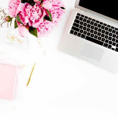 Düz uzanmış kadınların ofis masası. Dizüstü bilgisayarı olan bir kadın çalışma alanı, pembe şakayık buketi, beyaz arka planda aksesuarlar. Üst görünüm kadınsı arkaplan.
