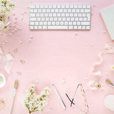Ofis masasında bilgisayar, leylak ve dosya var. Dergiler. Üst Manzara Düz Yatıyordu. Merkez ofis çalışma alanı. Pembe arka planda kadın moda aksesuarları