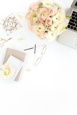 Tarz sahibi kadınların ofis masası. Laptop, bilgisayar, buket ranunculus ve güllerle çalışma alanı, beyaz arka planda pano. Düz yatıyordu. Üst görünüm.