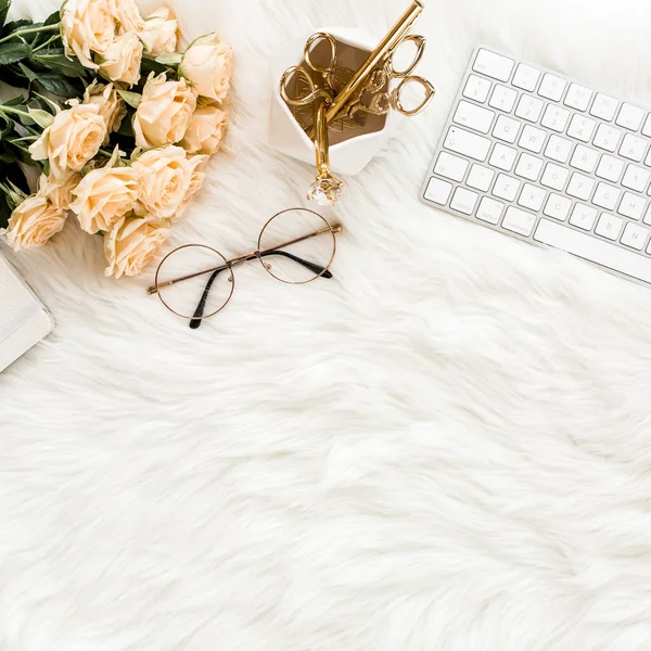 Female workspace with computer, roses flowers, golden accessories, diary, laptop, glasses on white background. Flat lay womens office desk. Top view.