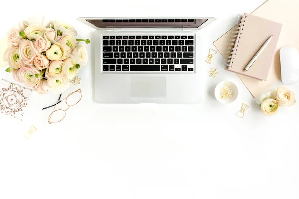 Stylized womens home office desk. Workspace with laptop, computer, bouquet ranunculus and roses, clipboard on white background. Flat lay. Top view.