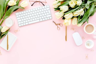 Bilgisayarlı kadın çalışma alanı, lale çiçekleri buketi, altın aksesuarlar, pembe arka planda günlük. Düz uzanmış kadınların ofis masası. Üst görünüm