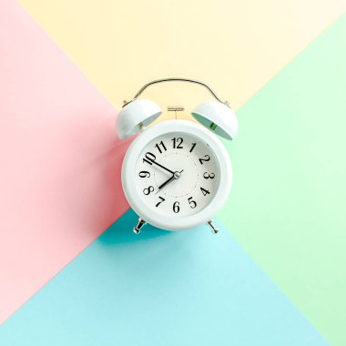 Renkli arka planda beyaz alarmlı saat. Moda minimal tarzı. Güzellik ve moda konsepti. Düz kompozisyon. Üst görünüm.