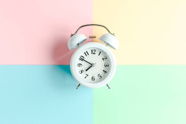 Renkli arka planda beyaz alarmlı saat. Moda minimal tarzı. Güzellik ve moda konsepti. Düz kompozisyon. Üst görünüm.
