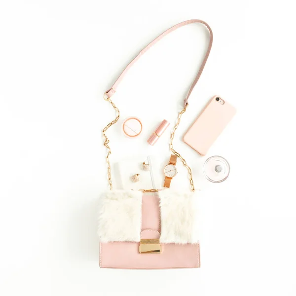 Dámská růžová taška s módními doplňky: hodinky, parfém, telefon, rtěnka, náušnice na bílém pozadí. Byt ležel, horní pohled — Stock fotografie