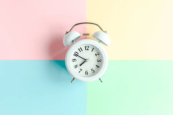 White alarm clock on colorful background. Trendy minimal style. Beauty and fashion concept. Flat lay composition. Top view. — Stock Photo, Image