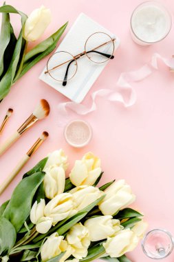 Lale çiçeği buketli, altın aksesuarlı, pembe arka planlı bir kadın çalışma alanı. Düz uzanmış kadınların ofis masası. Üst görünüm kadınsı arkaplan