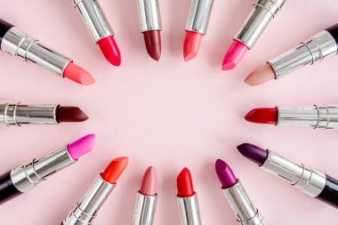 Pembe arka planda renkli ruj seti. Profesyonel dekoratif kozmetik ürünler. Düz kompozisyon güzelliği, moda. düz yatış, üst görünüm