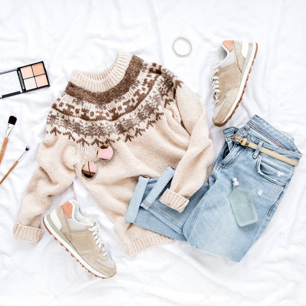 Female fashion look with stylish clothes and accessories. Womens warm sweater, jeans, sneakers. Modern and casual outfit. Flat lay, top view.