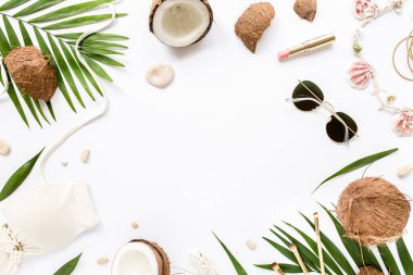 Kadınsı bej mayo plaj aksesuarları, tropikal palmiye yaprağı dalları, beyaz arka planda hindistan cevizleri ve mesaj için boş alan. Düz yatış, üst görünüm. 